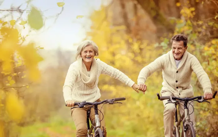 Senior couple riding bikes outdoors, smiling and enjoying retirement.